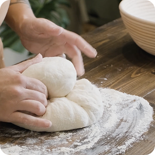 Hands kneading sourdough on a floured countertop