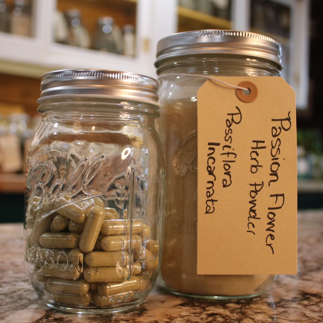 Two Ball mason jars with kraft paper labels - one containing capsules labeled "Passifolia Incarnata" and another with powder labeled "Passion Flower Herb Extract."