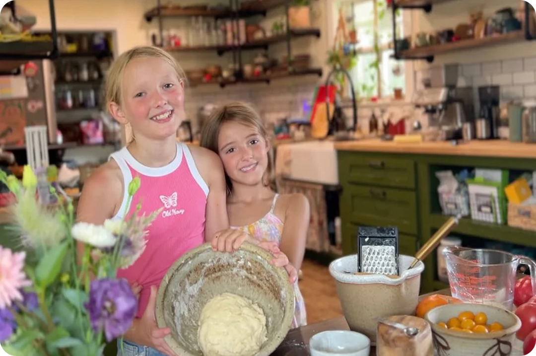 Jill's daughters in a kitchen holding a bowl of dough